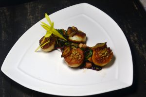 Sunflower Crusted Diver Scallops with Pumpkin Mousse, Tender Greens Petite Chard, Onion Brulee, Warm Pork Belly Dressing at 1700 Degrees Steakhouse